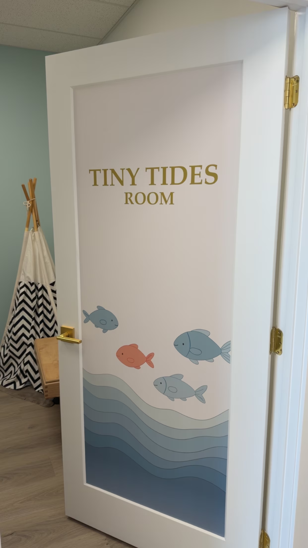 The Tiny Tides Room door, with painted fish swimming over ocean waves